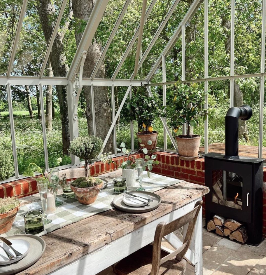 Black bioethanol fireplace next to a dinner table in the garden surrounded by greenery