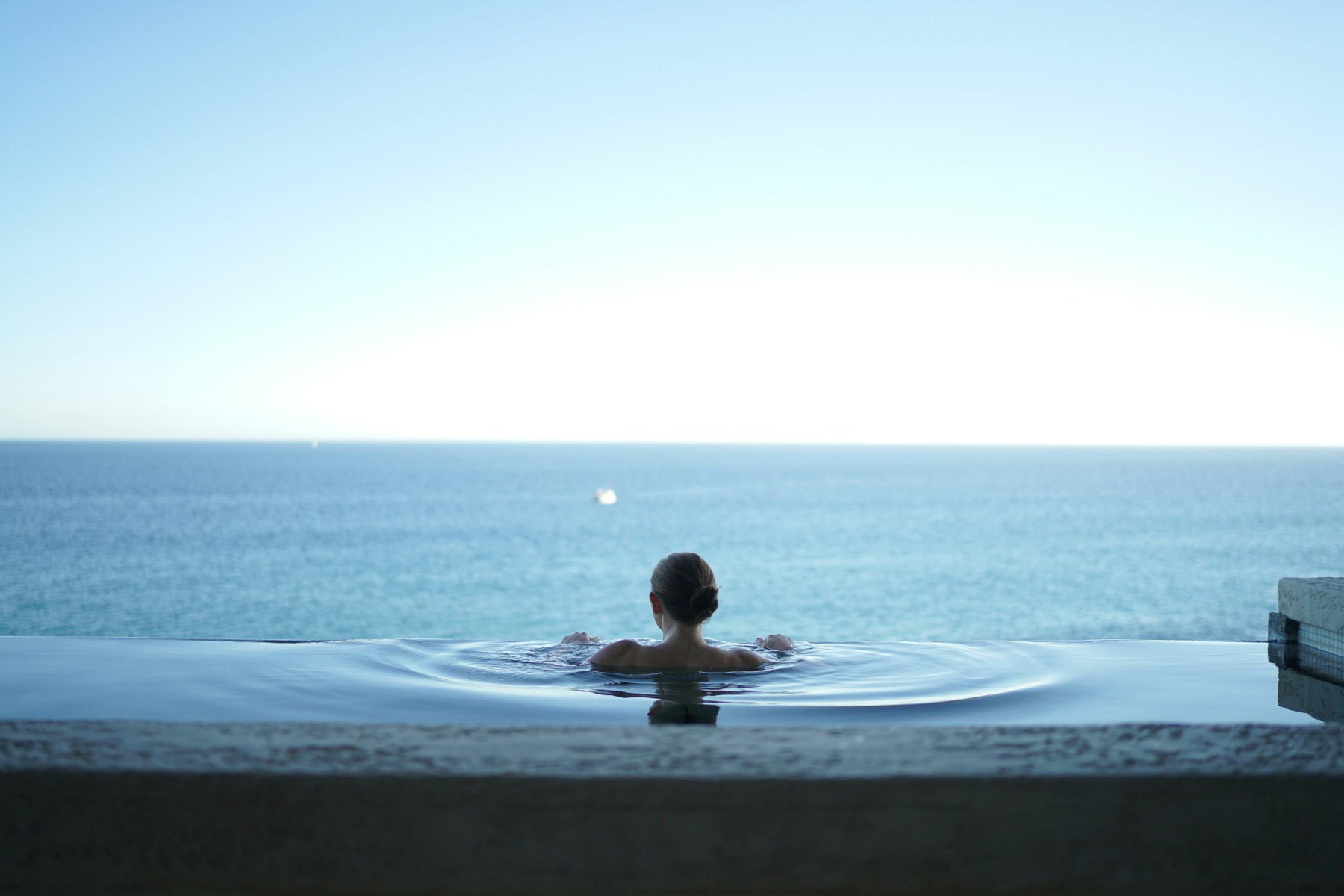 Woman in a water pool overlooking the sea