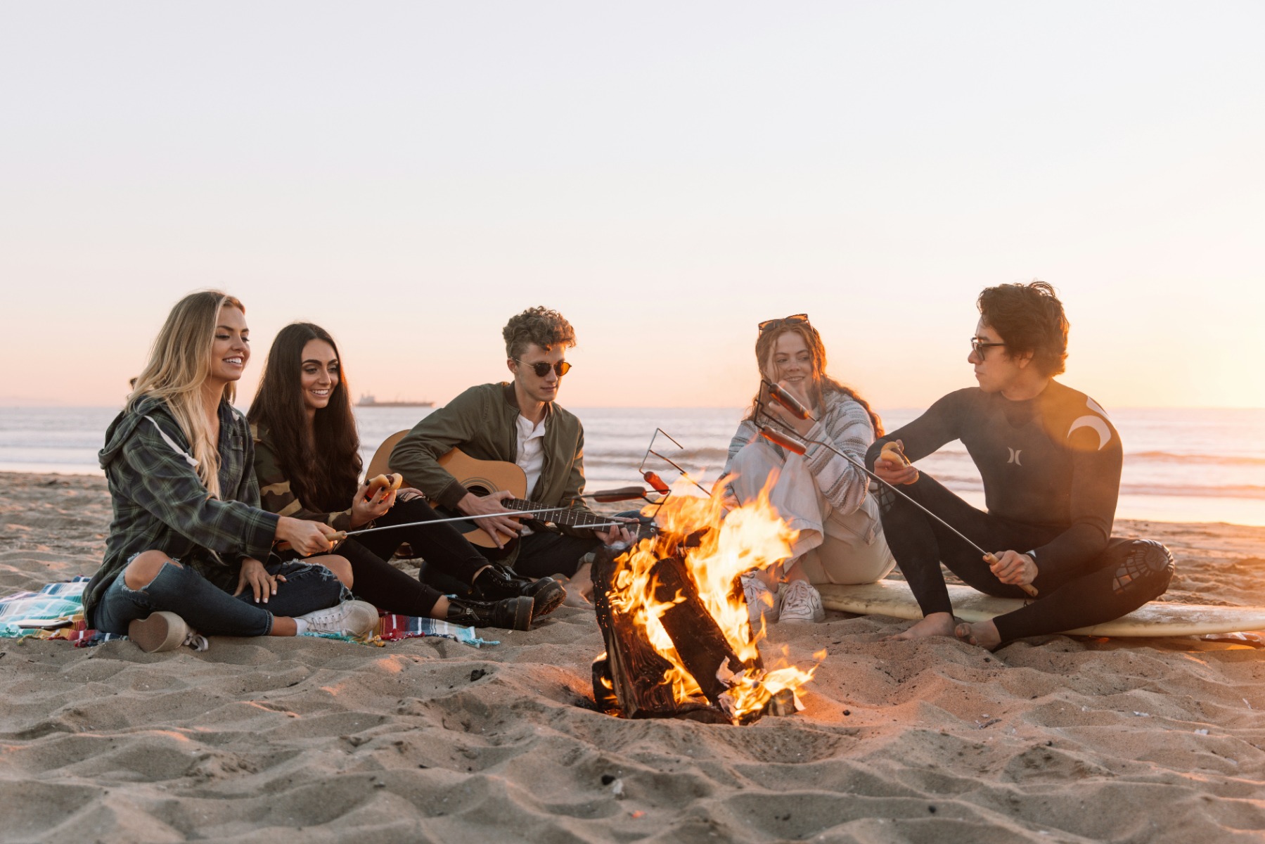 Group of people gathered around a fire on the beach