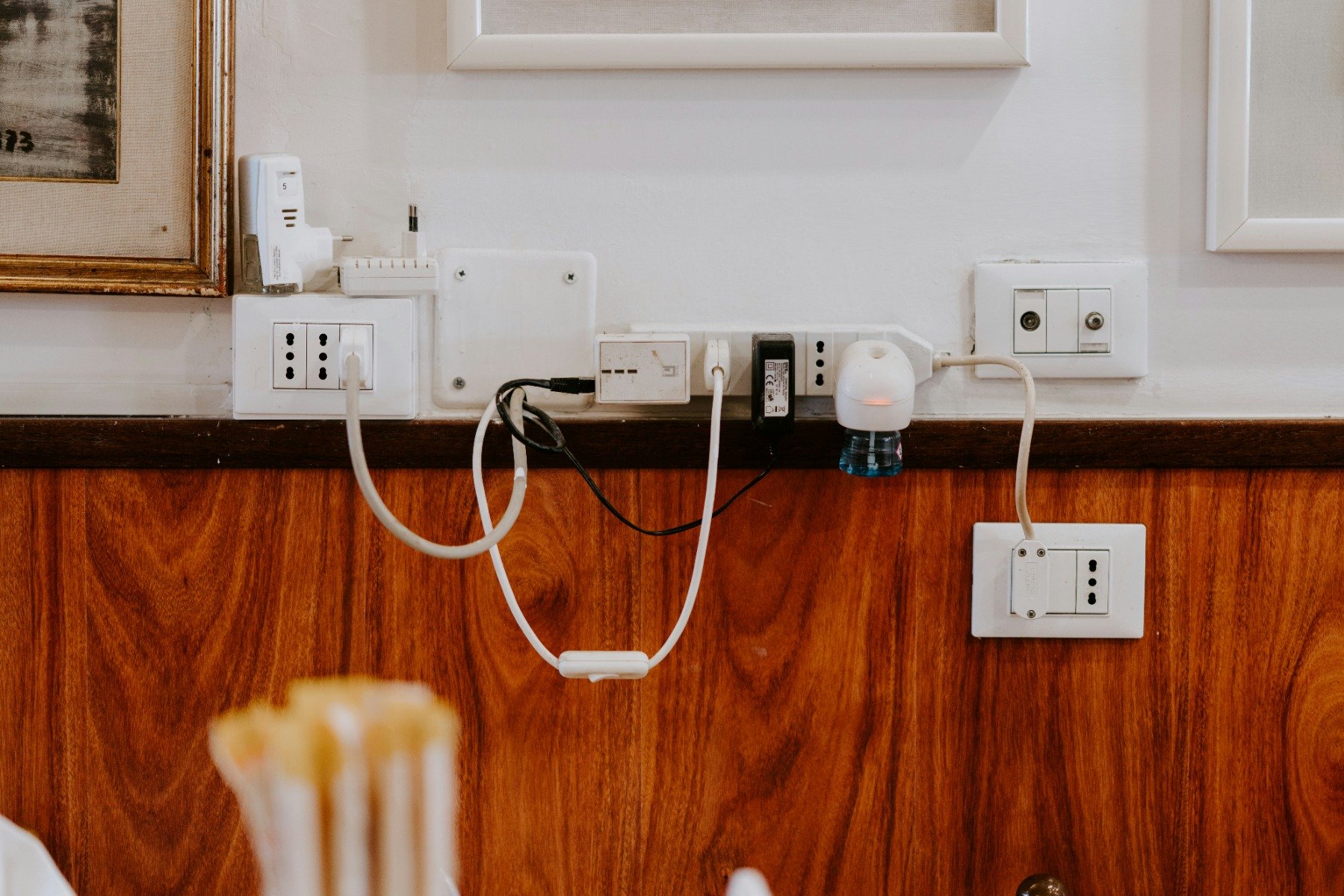 A jumble of electrical cords coming out of sockets in the wall