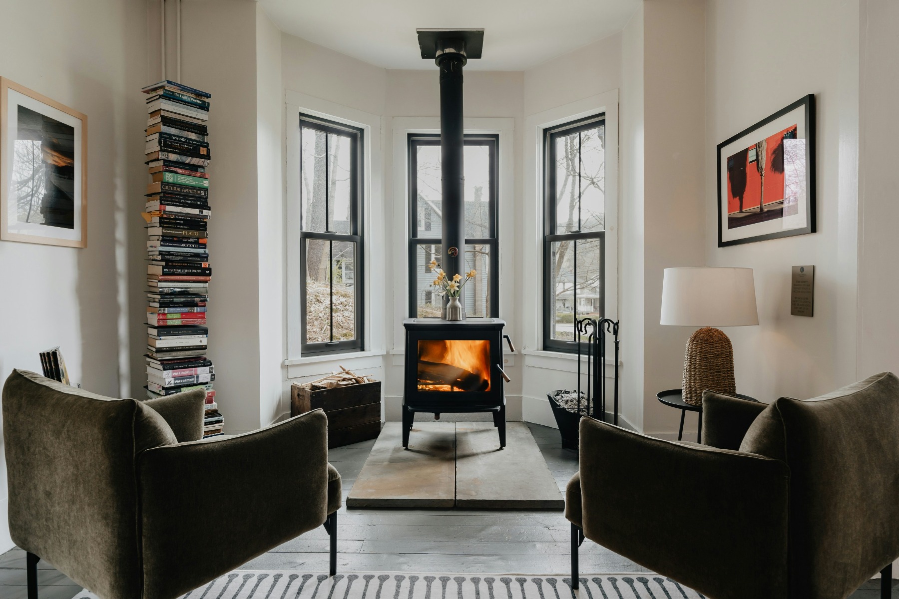 Black fireplace with long flue in between two chairs in a living room