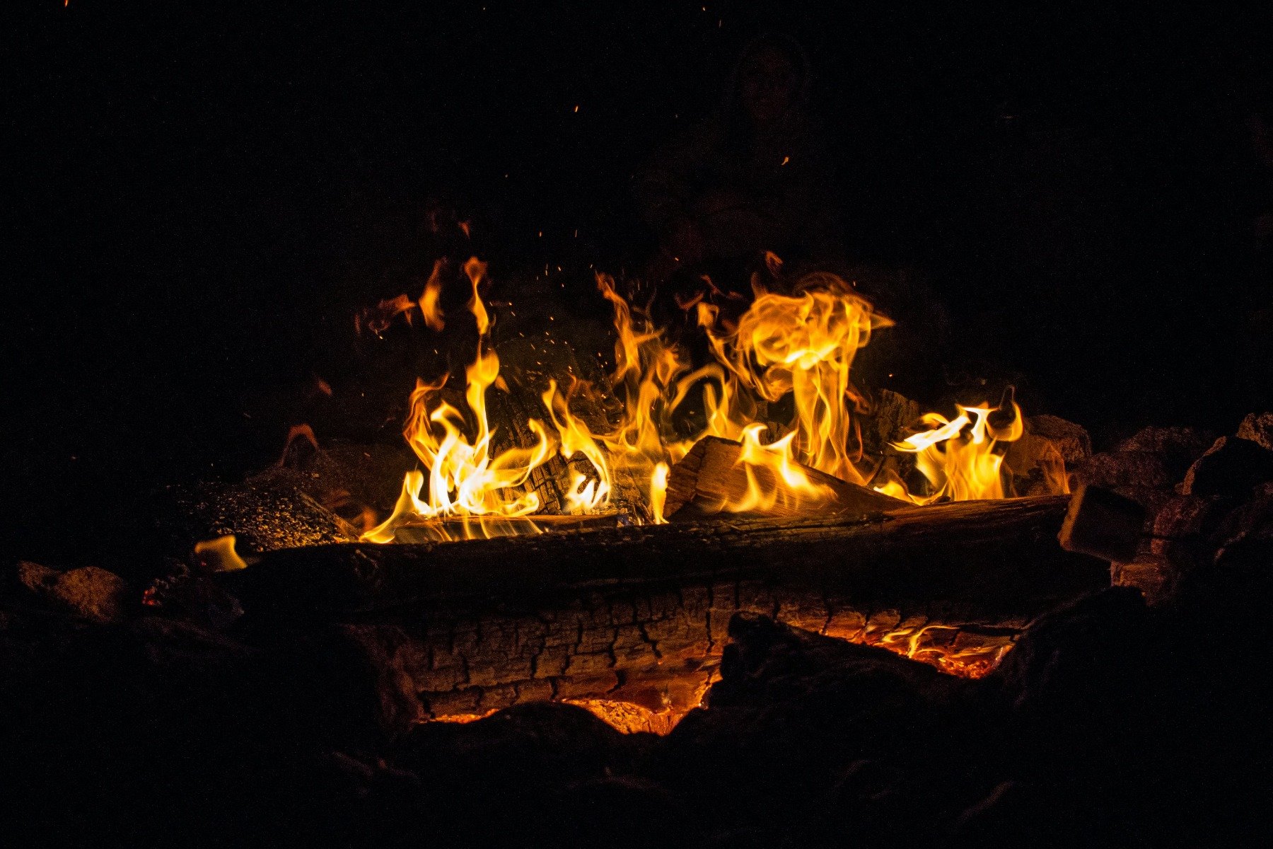 A log fire burning outside, illuminating the dark