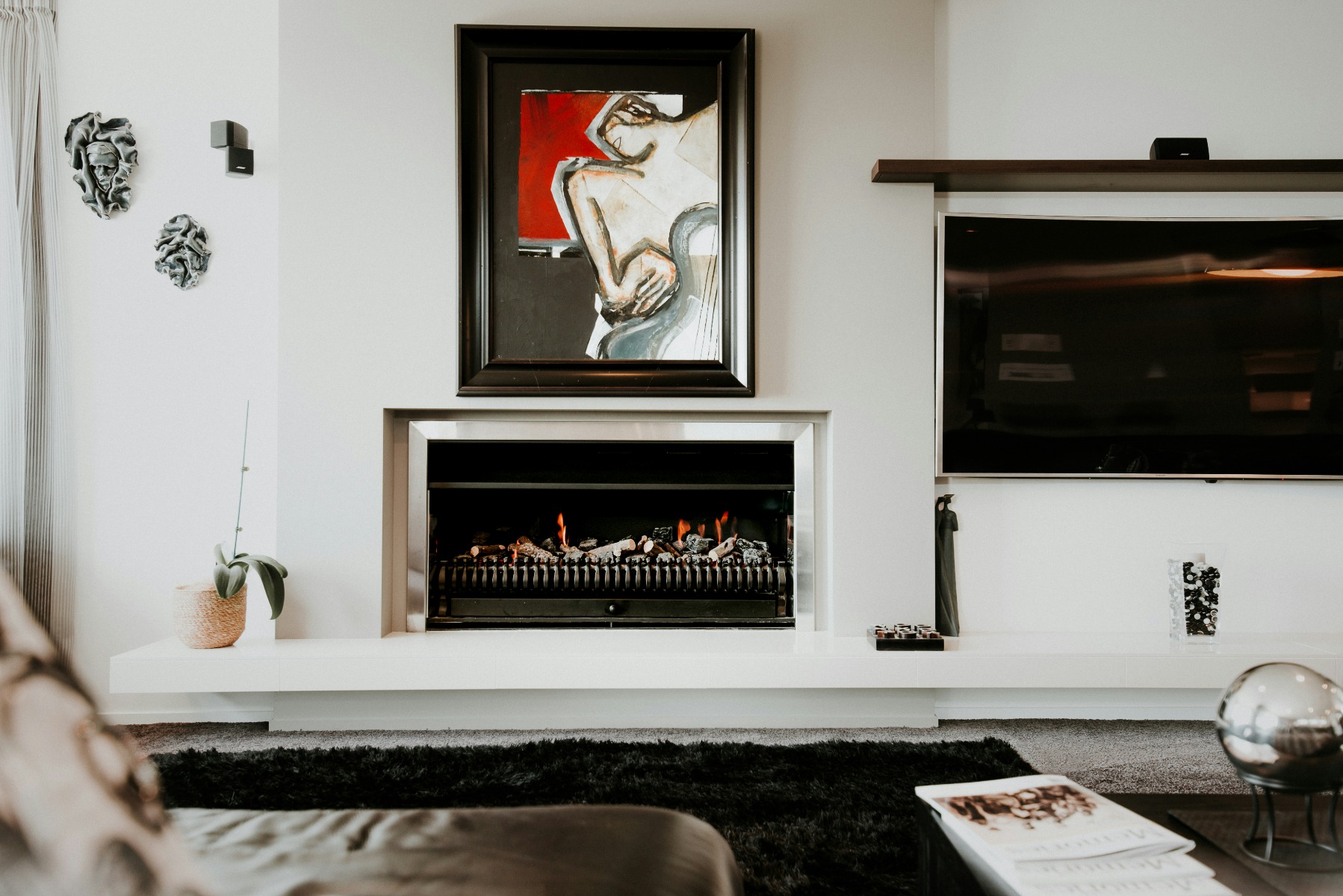 Abstract painting hanging over a fireplace in a white living room