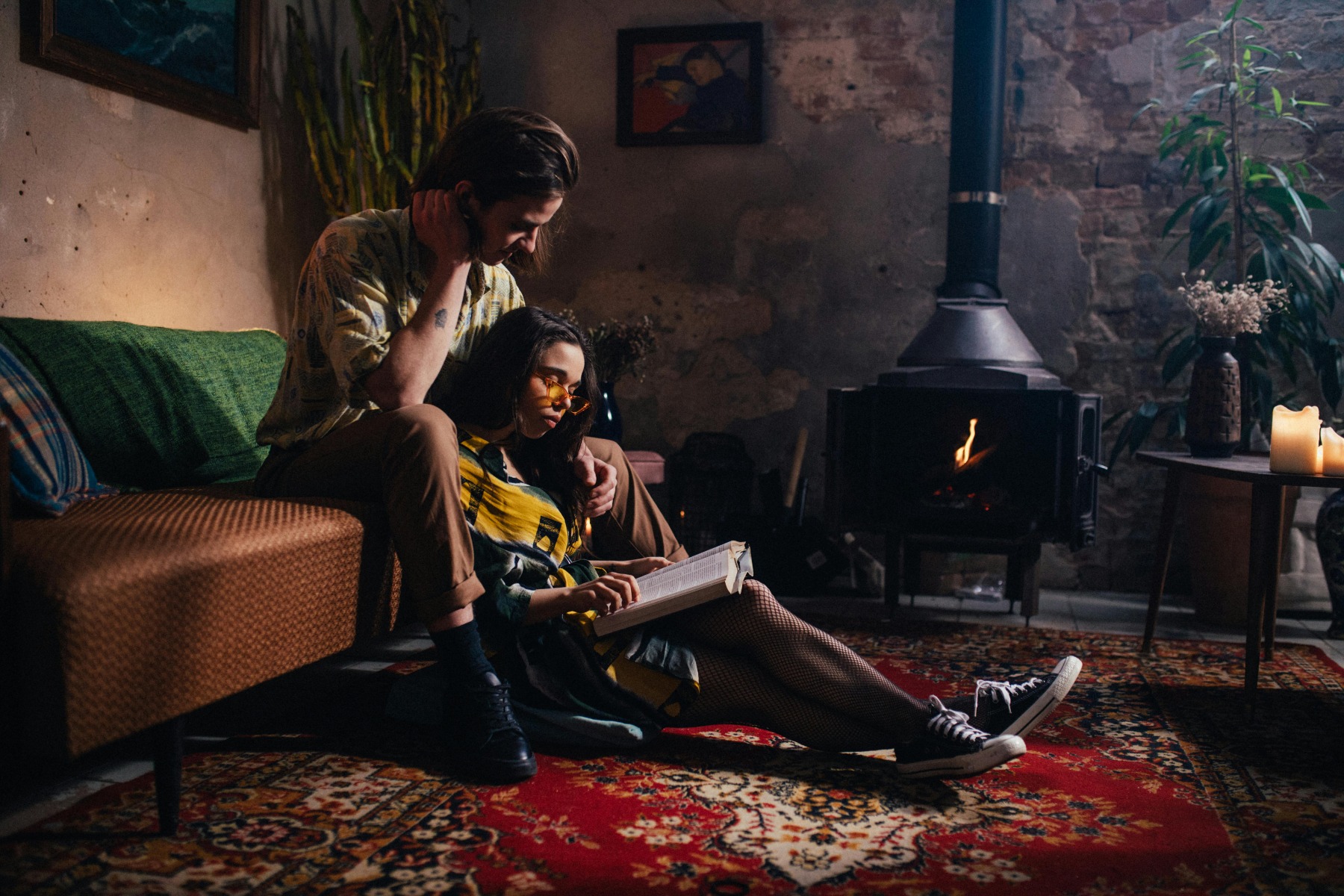 Two people are reading a book next to a black fireplace