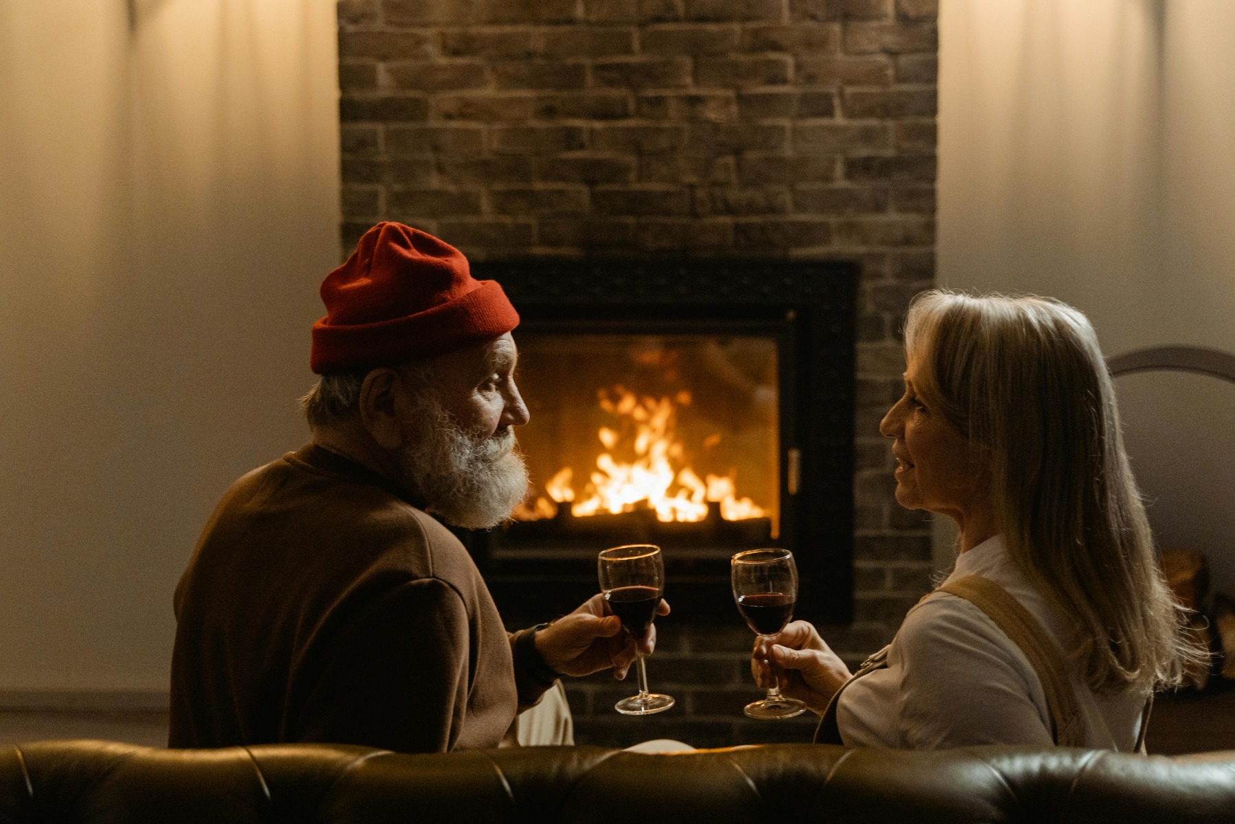 Two people drinking wine and having a date across a fireplace